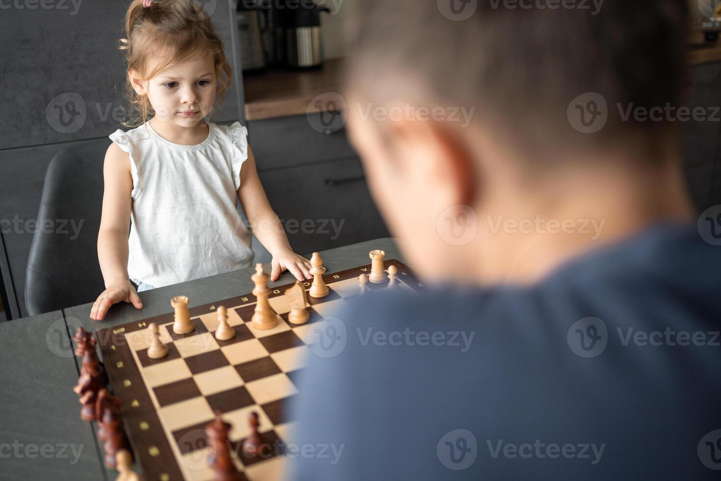 far undervisning hans liten dotter till spela schack på de tabell i Hem kök. de begrepp tidigt barndom utveckling och utbildning. familj fritid, kommunikation och rekreation. foto