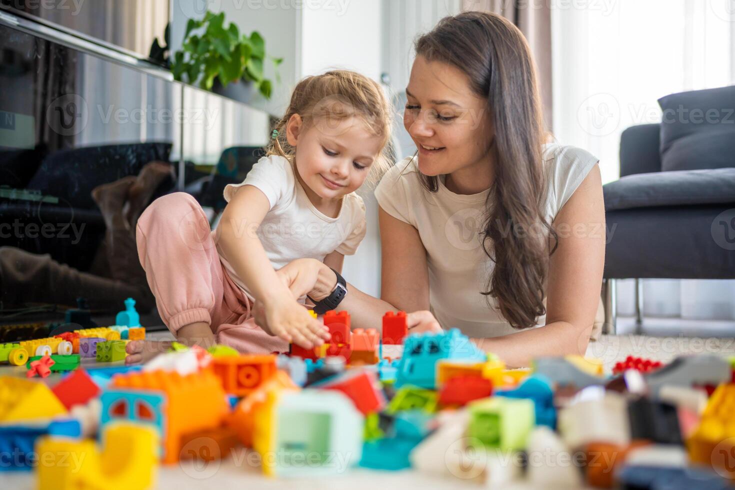 liten flicka spela med konstruktör leksak på golv i Hem med mamma eller kvinna barnvakt, pedagogisk spel, familj på Hem spendera fritid aktiviteter tid tillsammans begrepp foto