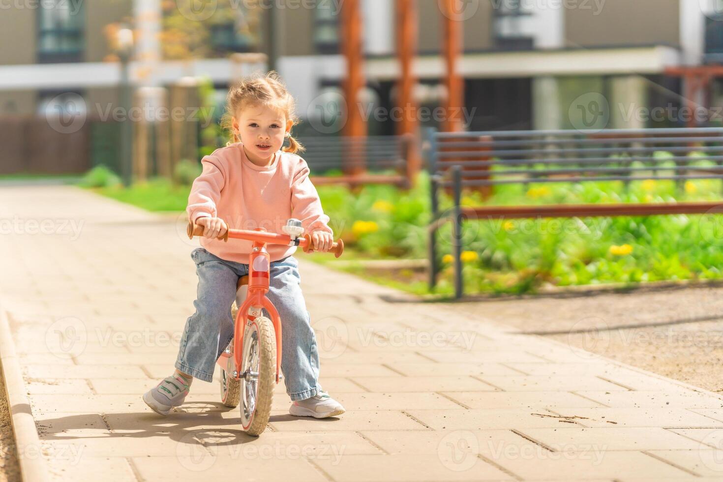 liten flicka ridning balans cykel i de gård av de bostad i Prag, Europa foto