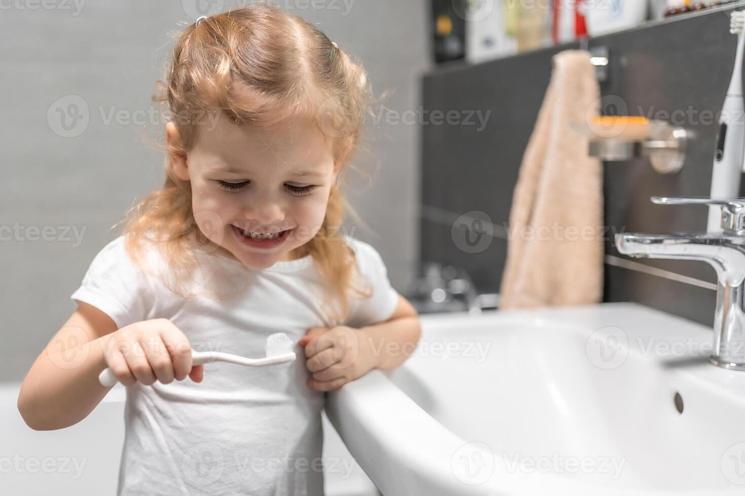 Lycklig litet barn flicka pensling tänder i de bad foto