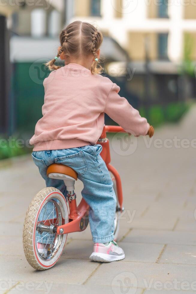 liten flicka ridning balans cykel i de gård av de bostad i Prag, Europa foto