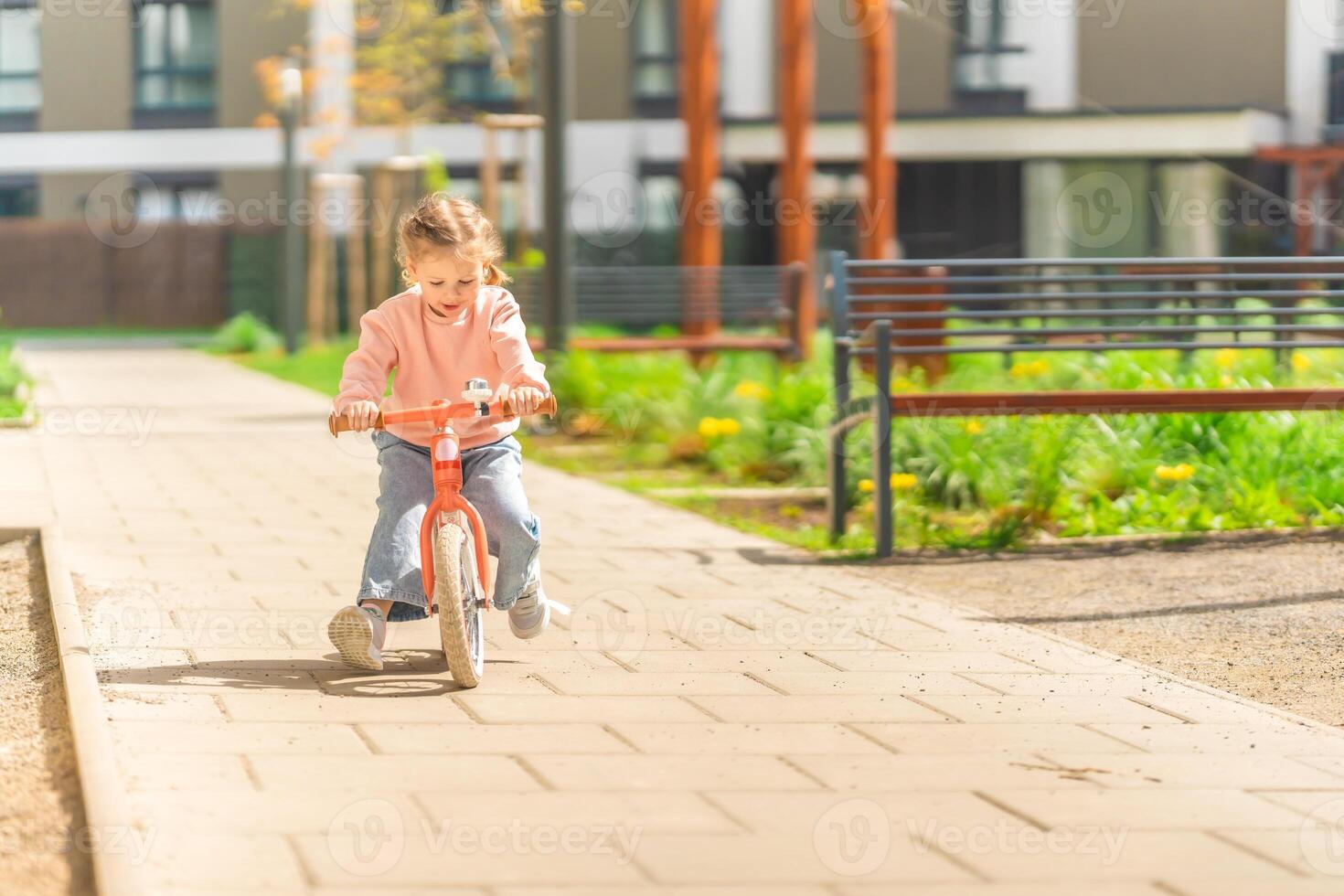 liten flicka ridning balans cykel i de gård av de bostad i Prag, Europa foto