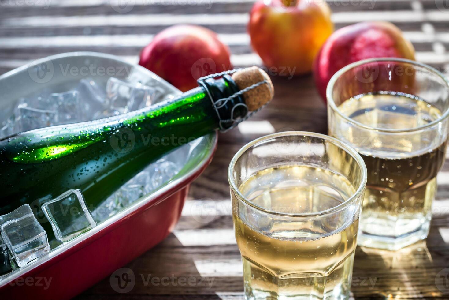 flaska och två glasögon av cider på de trä- bakgrund foto