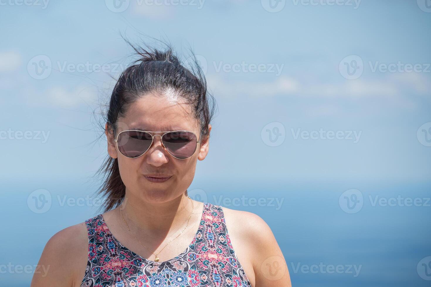 porträtt av en latinamerikan kvinna bär glasögon med en mjuk ljus blå himmel bakgrund. foto