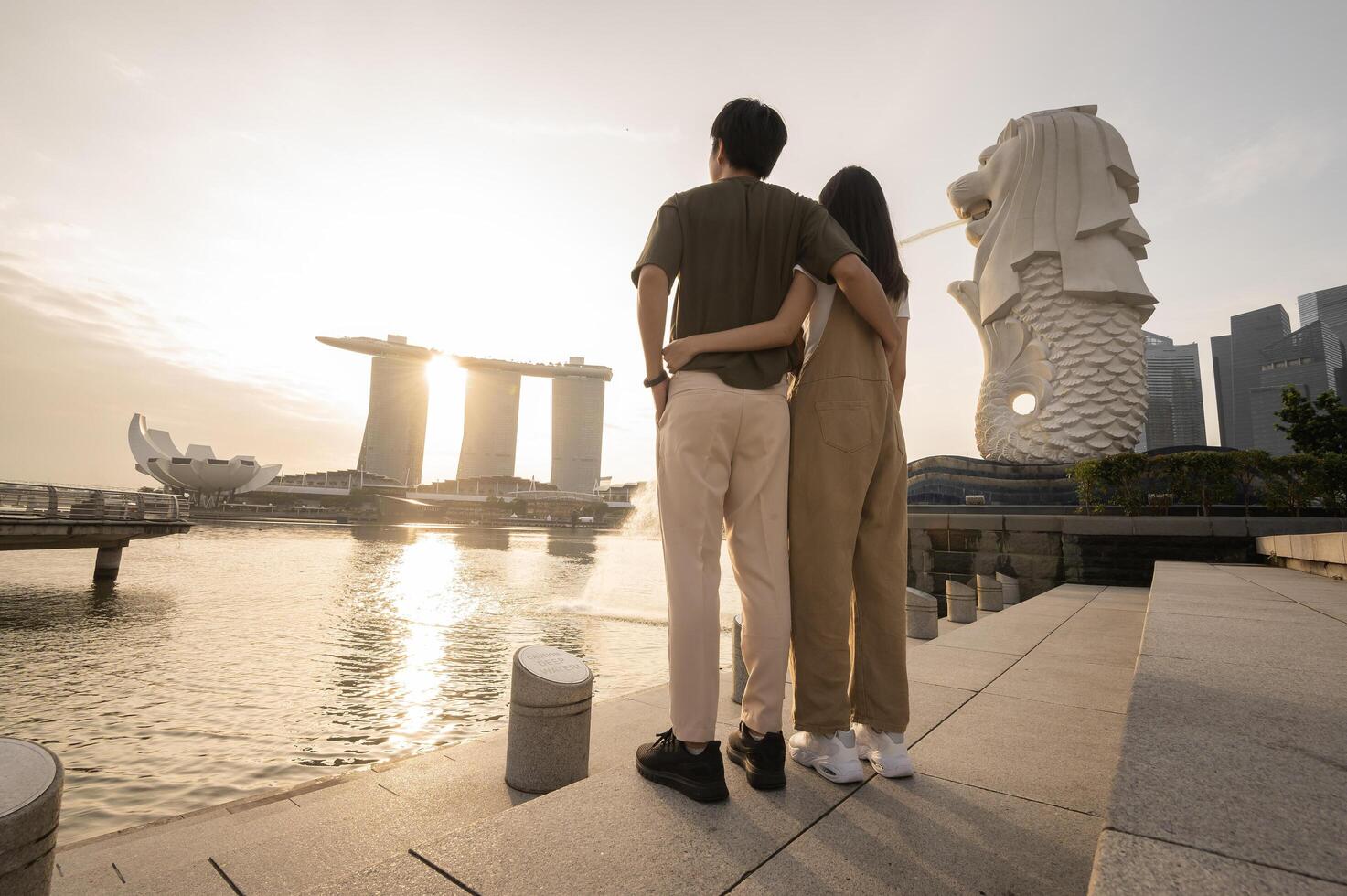 merlion fontän i främre av de marina bukt sandstrand med ung asiatisk par av kärlek turist. foto