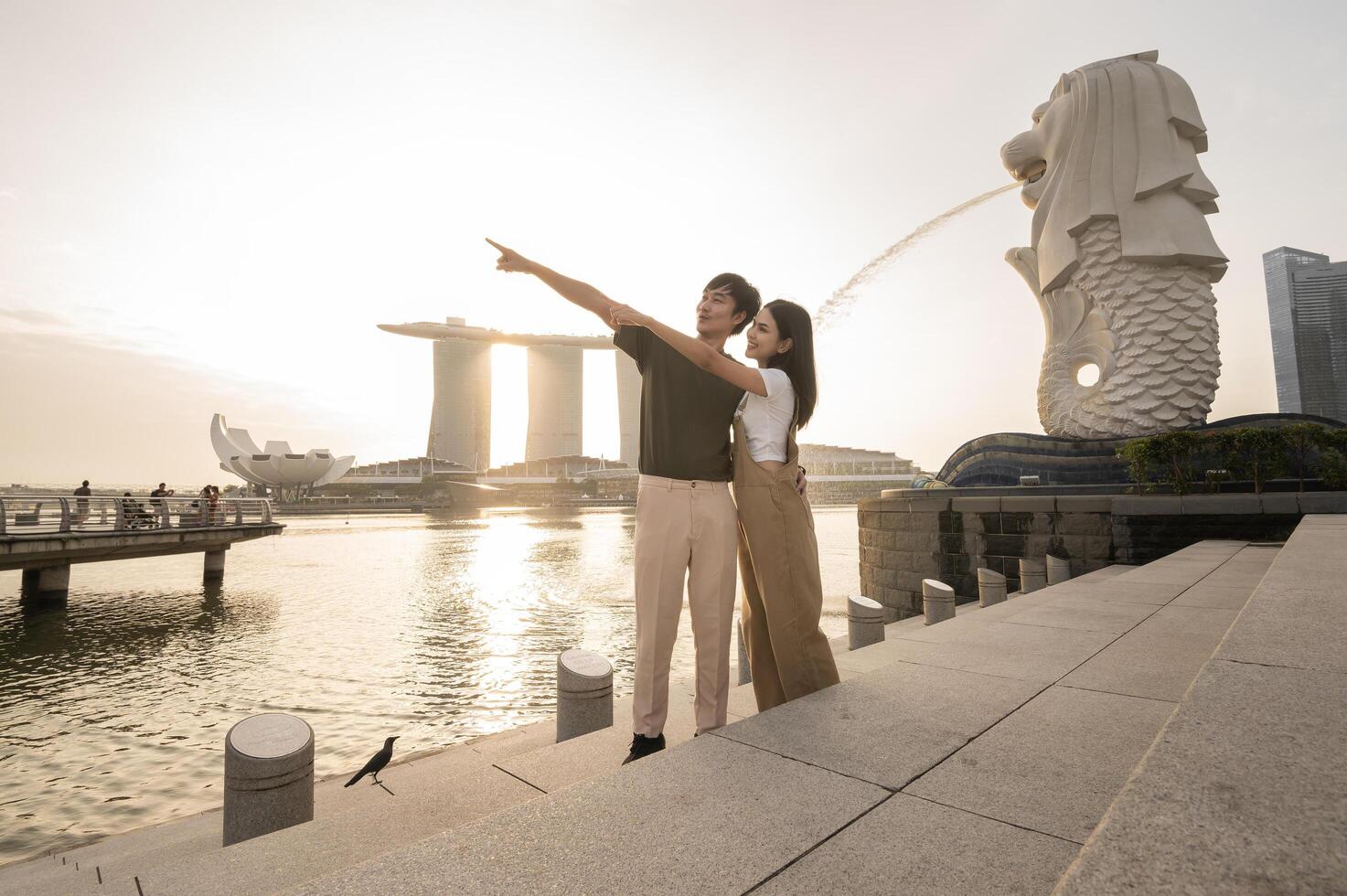 merlion fontän i främre av de marina bukt sandstrand med ung asiatisk par av kärlek turist. foto