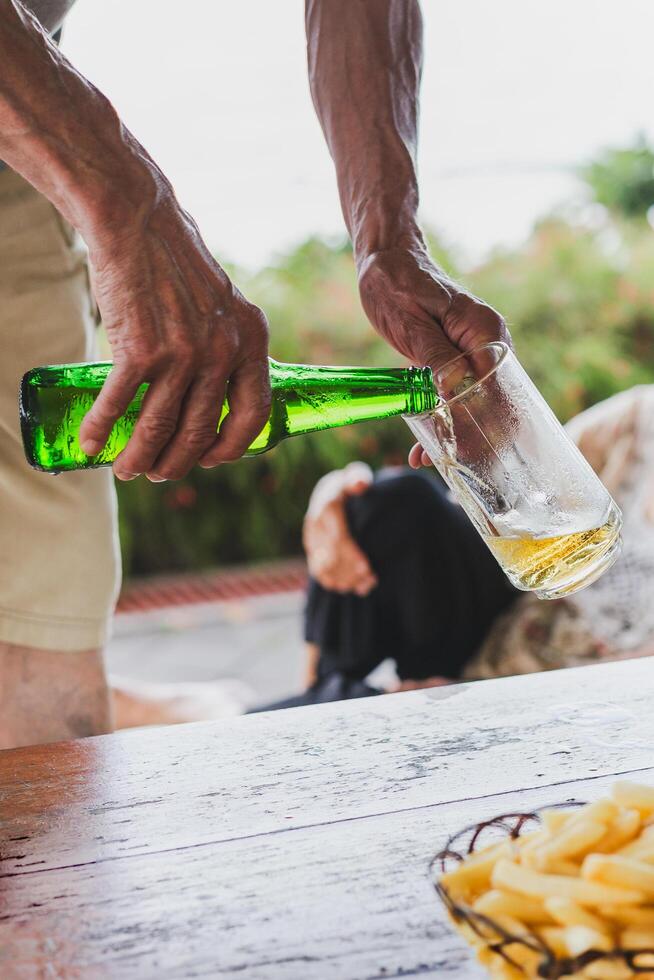 hand av en man häller öl från en flaska i en glas. foto