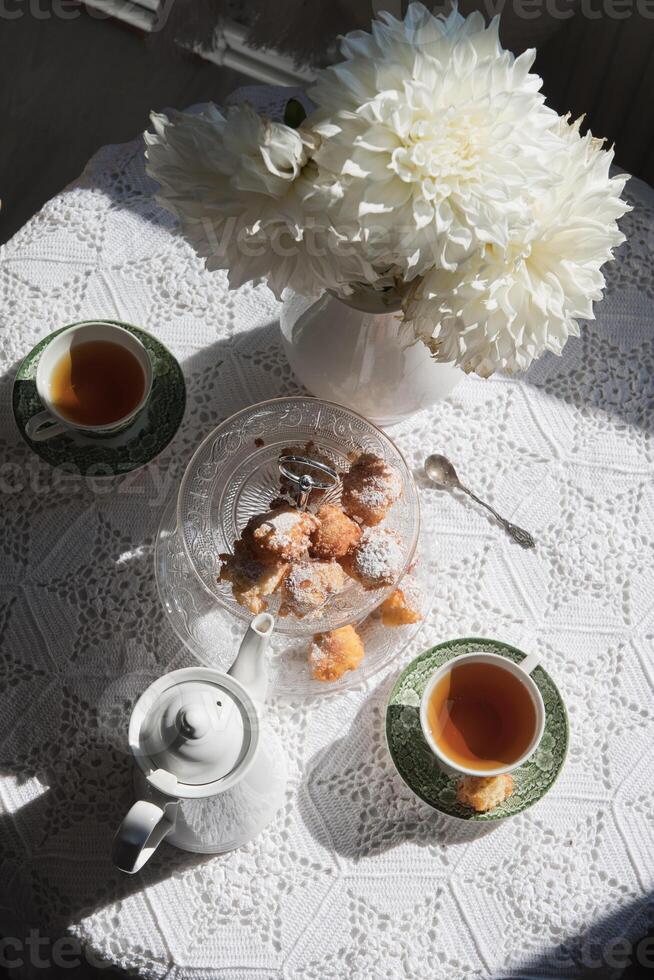 engelsk stil te ha sönder, fortfarande liv med blommor och munkar i de morgon- Sol foto