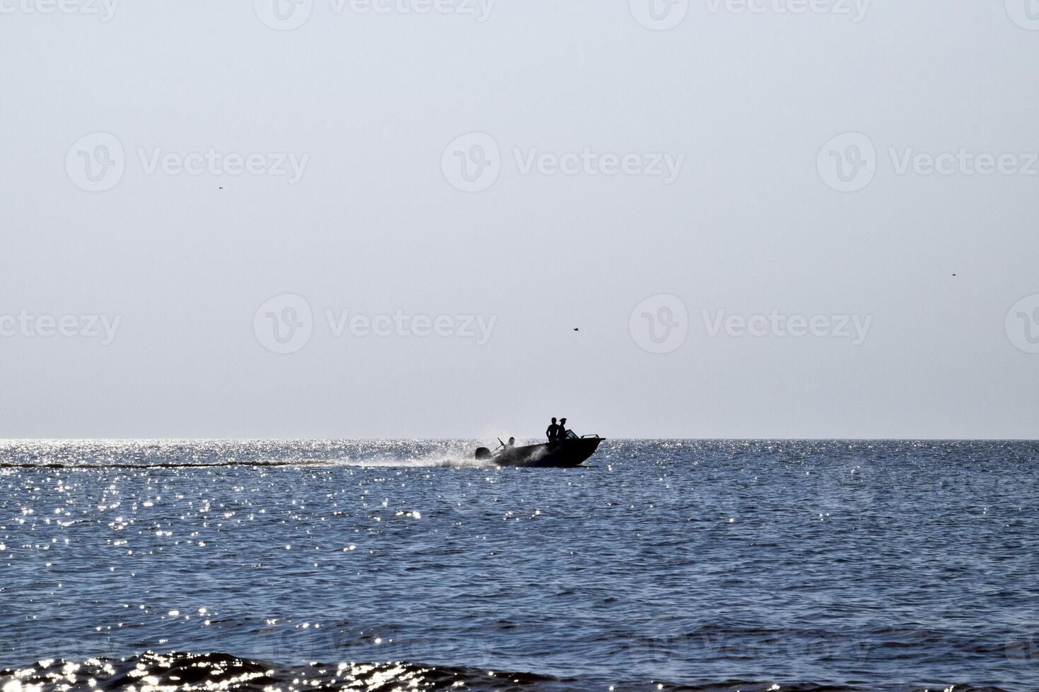 de båt rusar förbi de hav. i de båt människor. marinmålning i de kväll. silhuett av en motor båt och människor i den mot de bakgrund av de hav distans foto