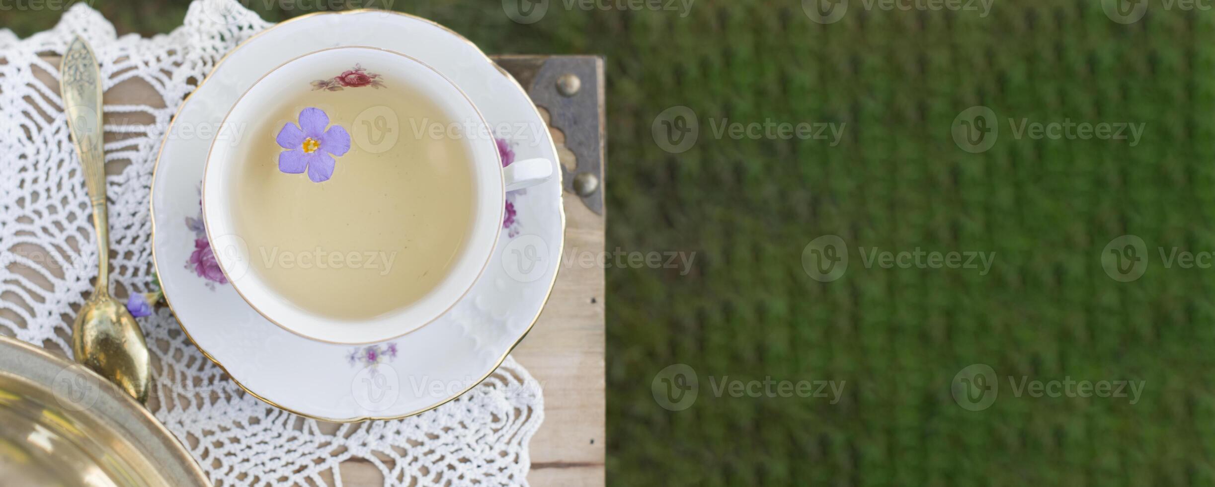 porslin kopp med te och blomma flyter i te, årgång fortfarande liv, topp se foto