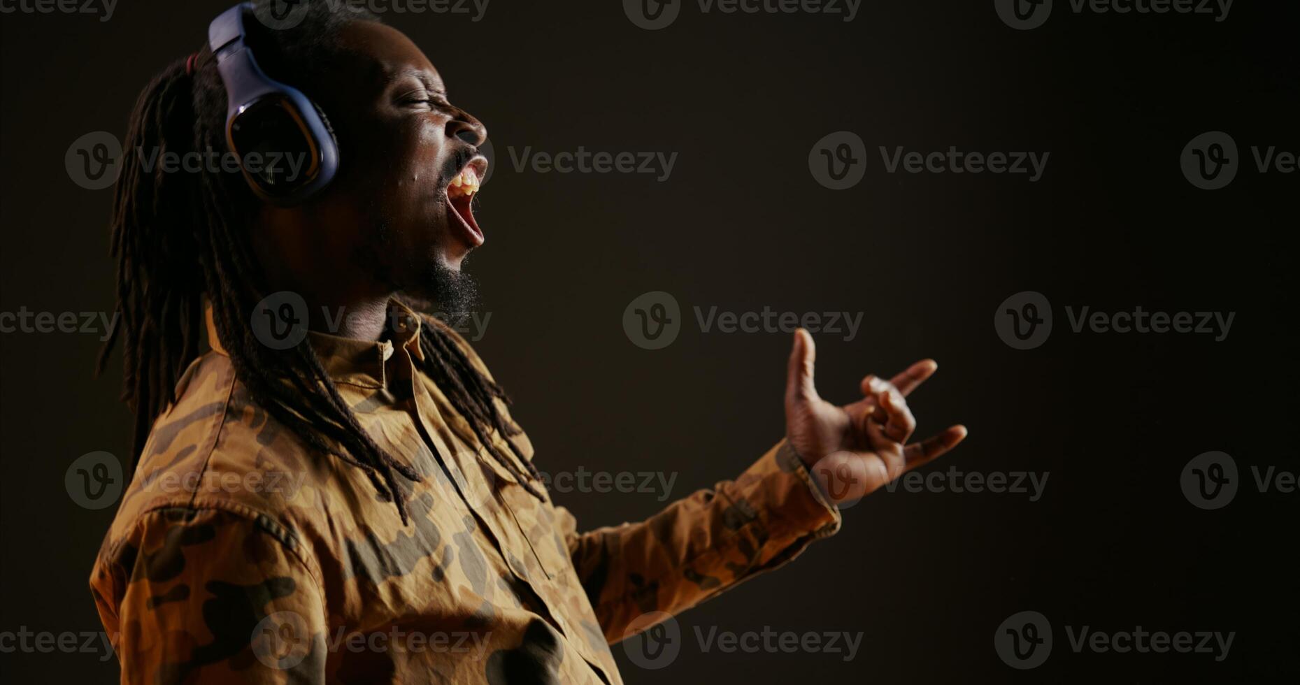 Häftigt person spelar luft gitarr och lyssnande till musik på kamera, låtsas till spela imaginär instrument och skapa låtar. afrikansk amerikan man har roligt med låtar på headset, musikalisk aktivitet. foto