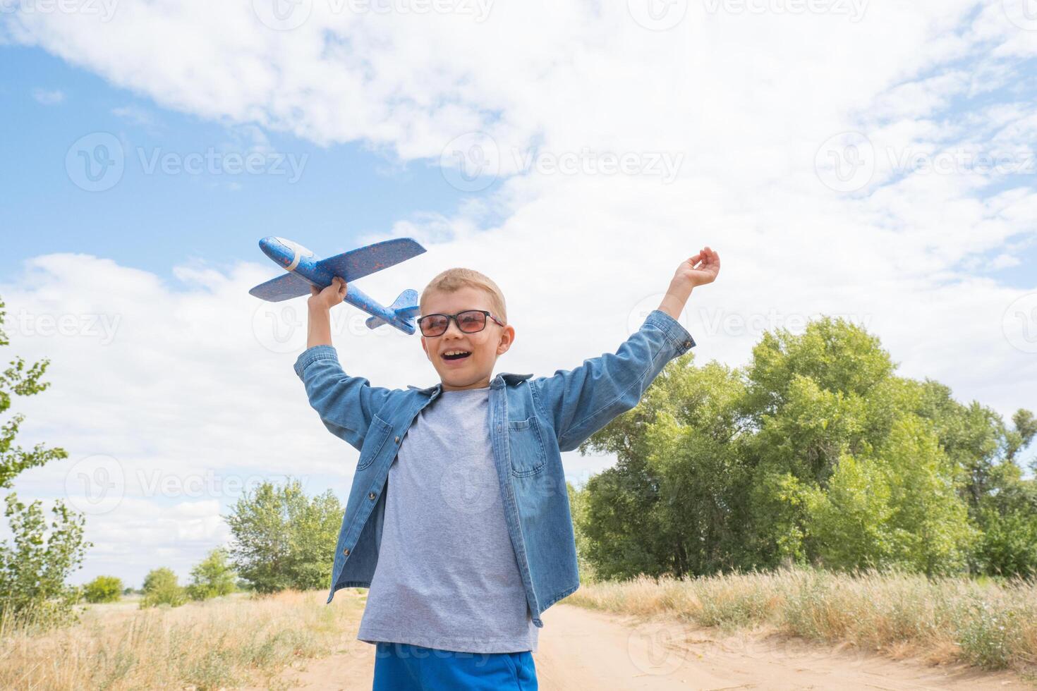 porträtt av en Lycklig barn spelar med en leksak flygplan mot en blå himmel i ett öppen fält foto