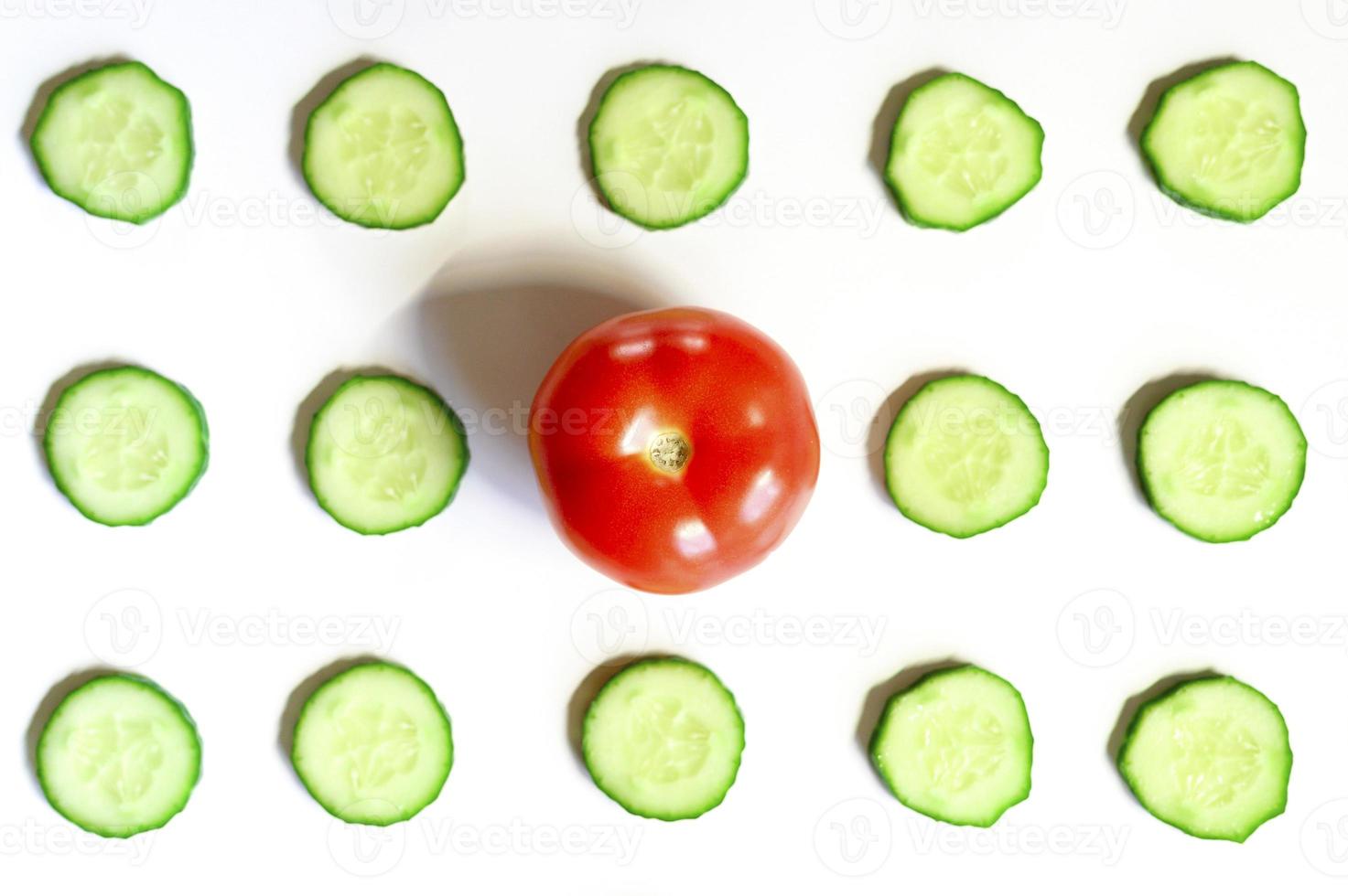 upprepande mönster av skivade halvcirklar av färska råa grönsaksgurkor för sallad och en hel tomat foto