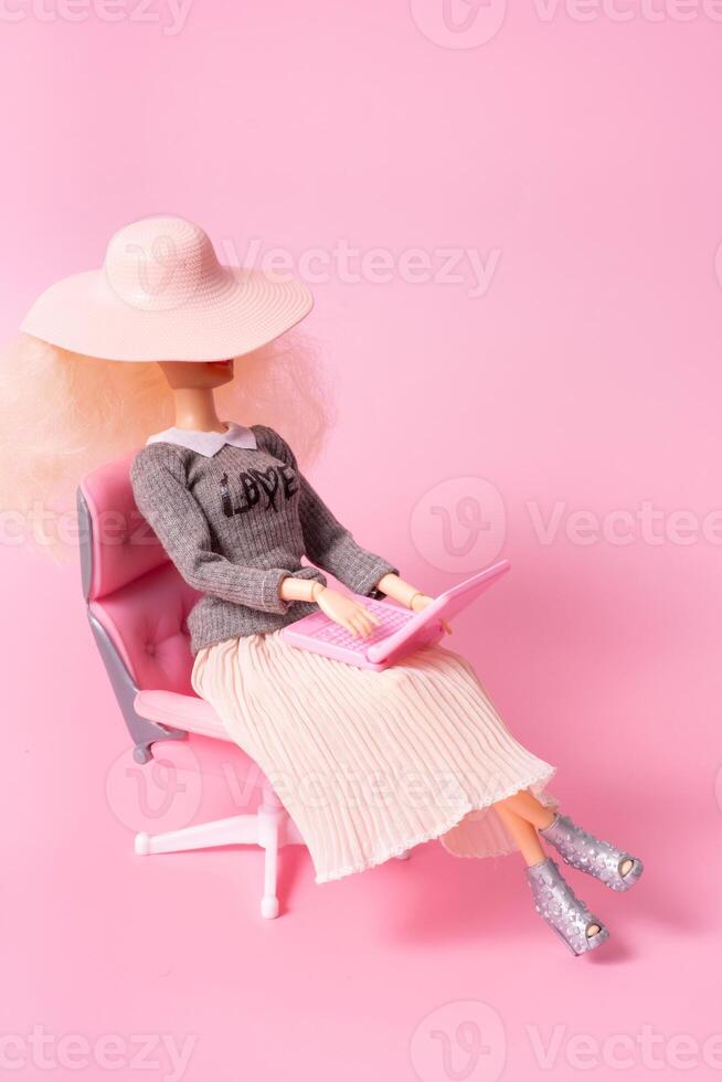 docka med bärbar dator i stol på rosa bakgrund. arbetssätt på Hem, frilans kreativ begrepp. foto