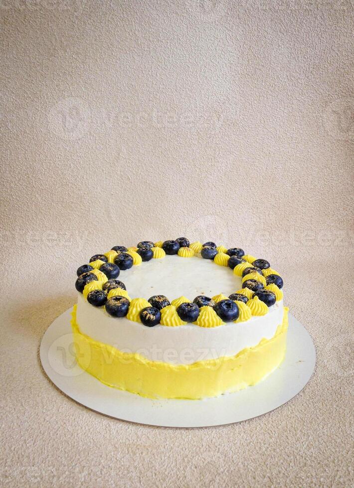 födelsedag vit och gul kaka med blåbär på en vit tallrik på en ljus bakgrund foto