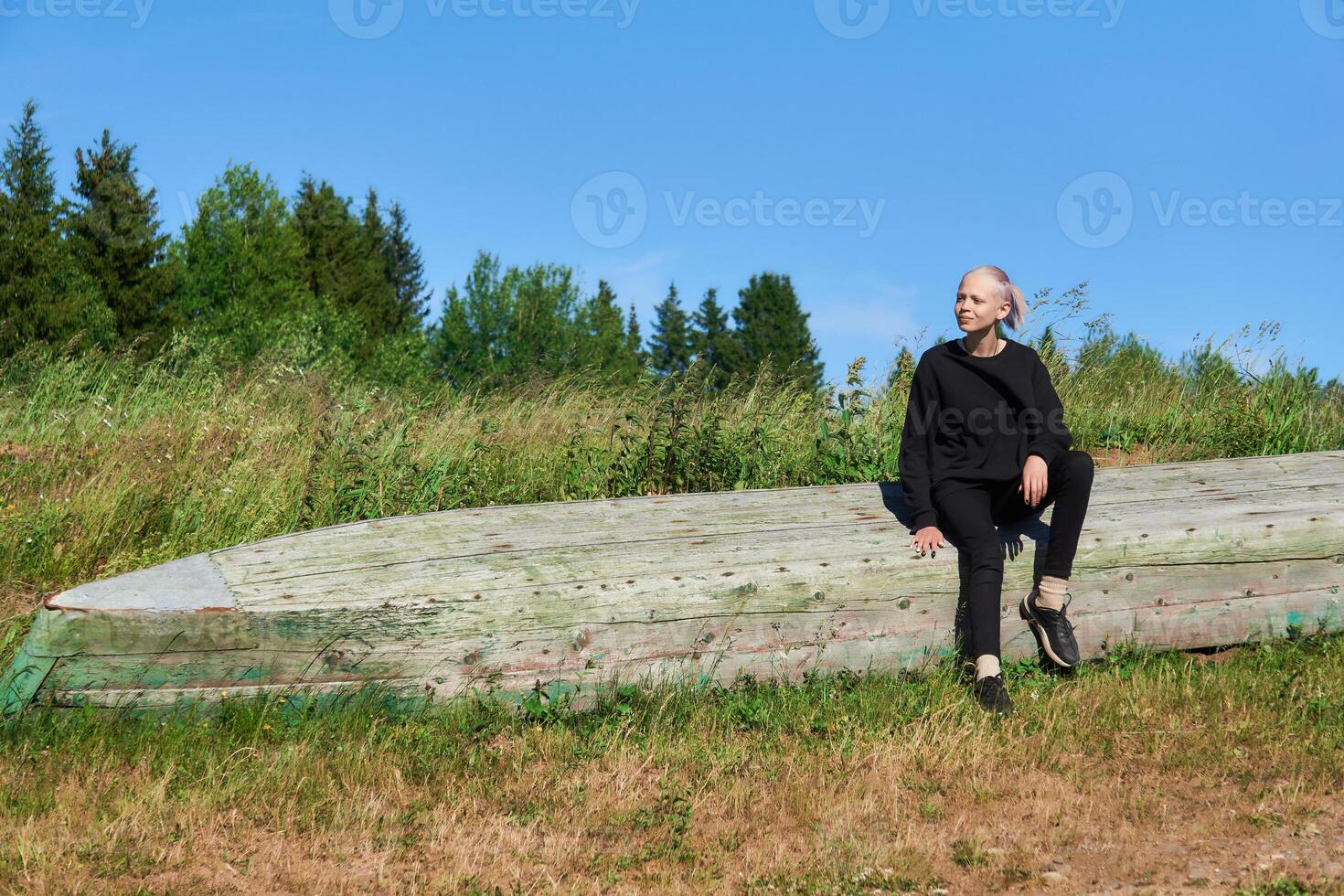 Tonårs flicka Sammanträde på ett upphävde båt på de Strand foto