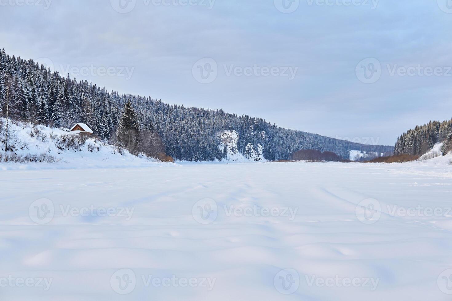 vinter- landskap med en bred frysta flod i en snöig trädbevuxen dal foto