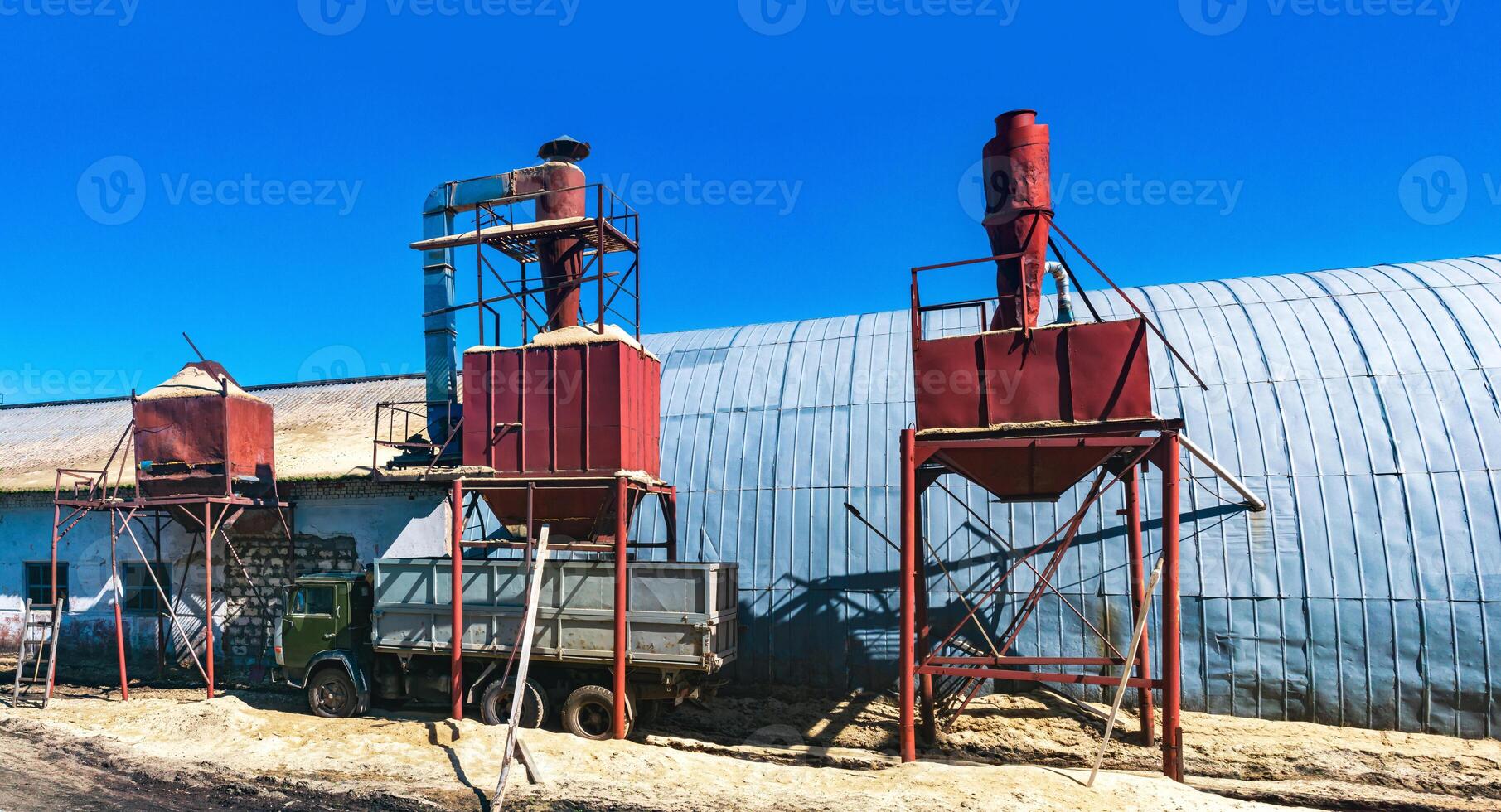 bunkra silos för läser in sågspån Nästa till de hangar, som hus de träbearbetning industri foto