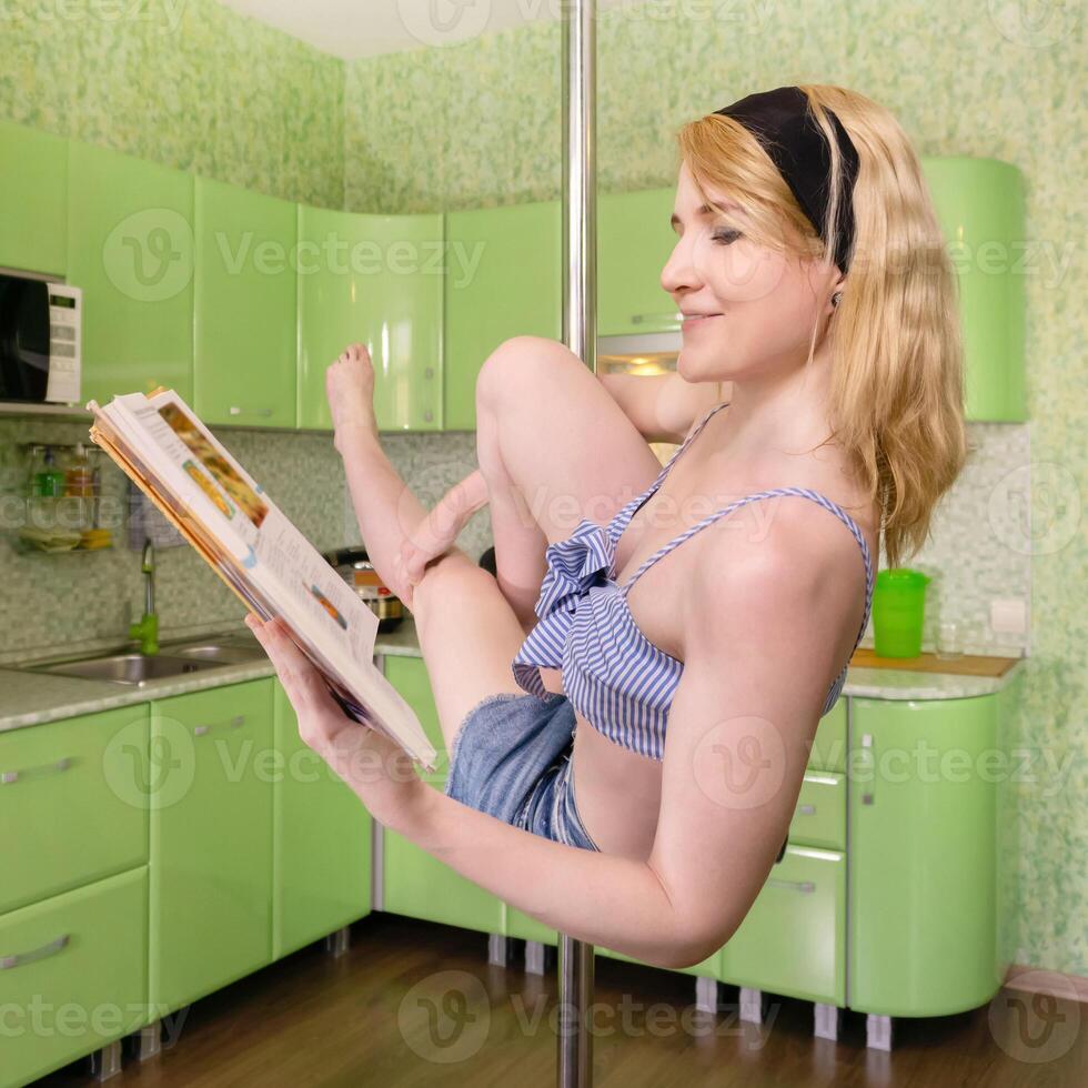 ung kvinna läser kokbok medan utövar i Pol dansa på Hem foto