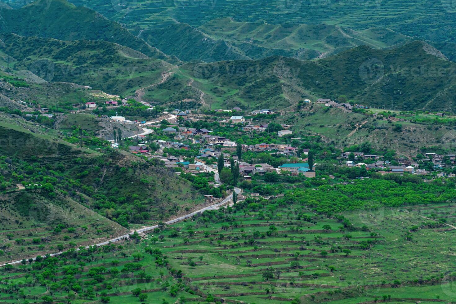 antenn se av en by i en berg dal bland trädgårdar och fält foto