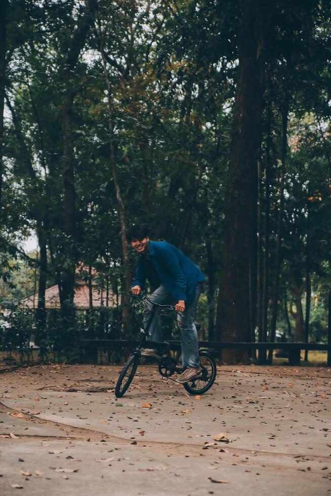 ung stilig skäggig man tar en ha sönder medan reser de stad med hans cykel använder sig av hans digital läsplatta ser bort eftertänksamt foto