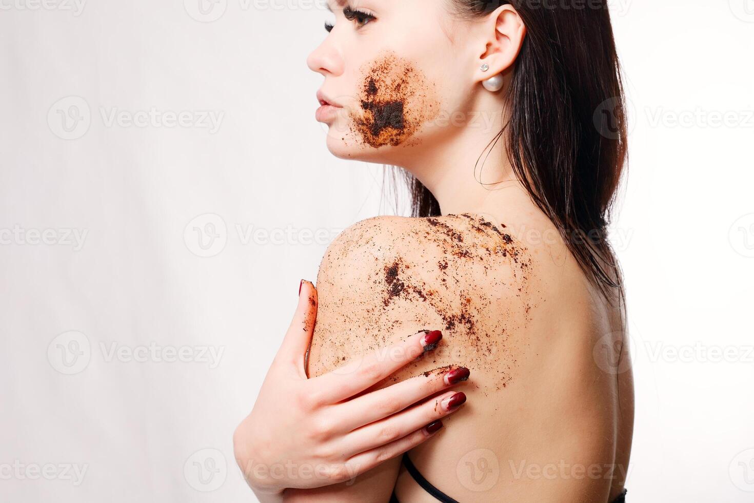 brunett kvinna rengör de hud av de kropp kaffe skrubba foto