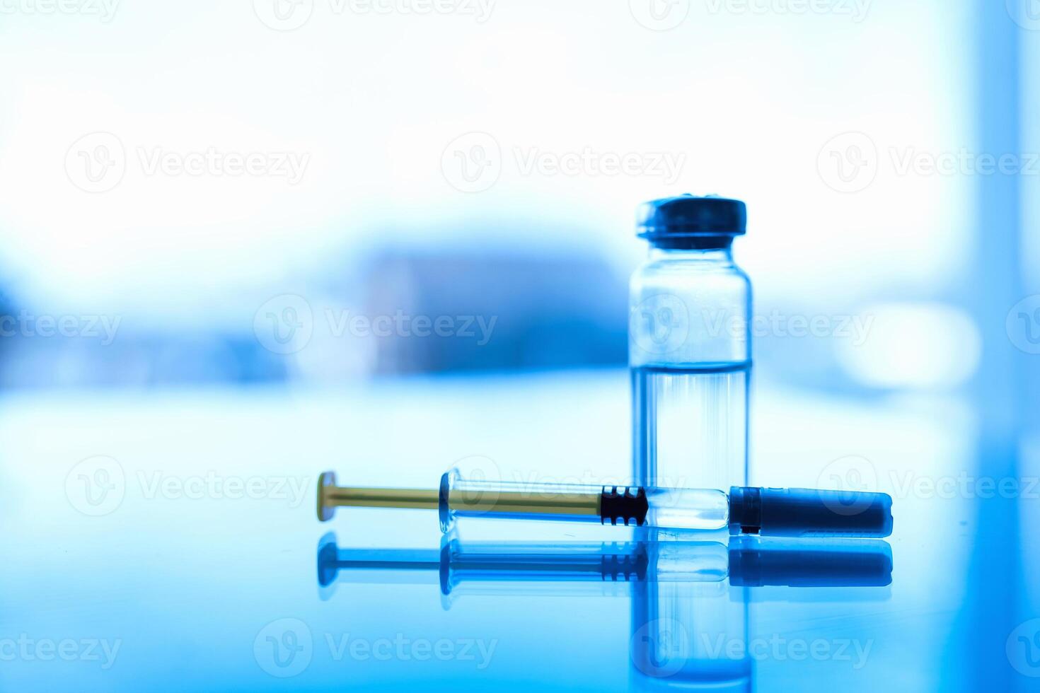ampuller av medicin och spruta på en blå glas tabell med fönster bakgrund foto