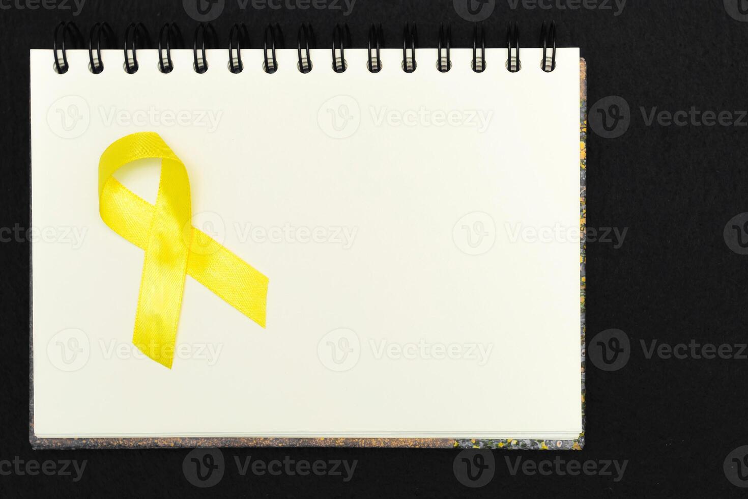 gyllene band för barn som en symbol av barndom cancer medvetenhet på en vit anteckningsblock. värld cancer dag. foto