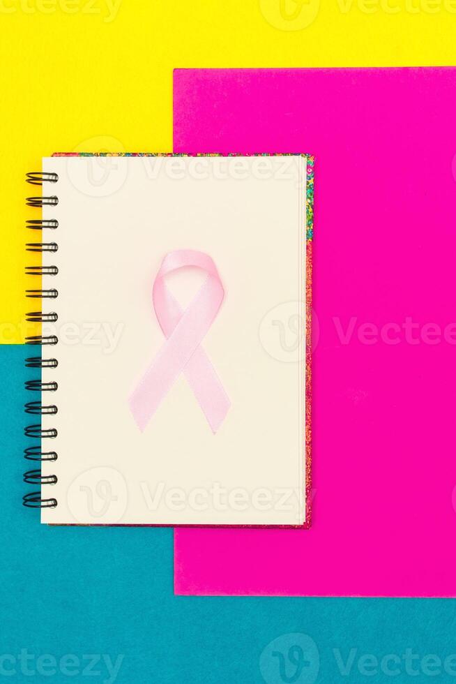 rosa band för bröst cancer medvetenhet, symbolisk rosett Färg höjning medvetenhet på människor levande med kvinnors bröst tumör sjukdom. rosett isolerat med klippning glitter blå bakgrund foto