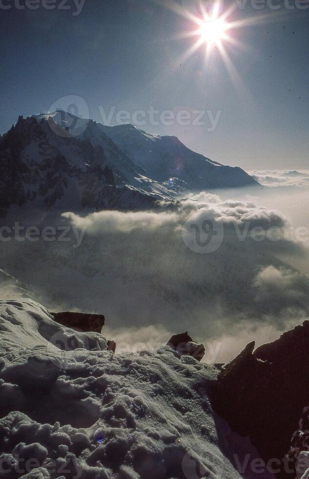 de Sol lyser över en snöig berg räckvidd foto