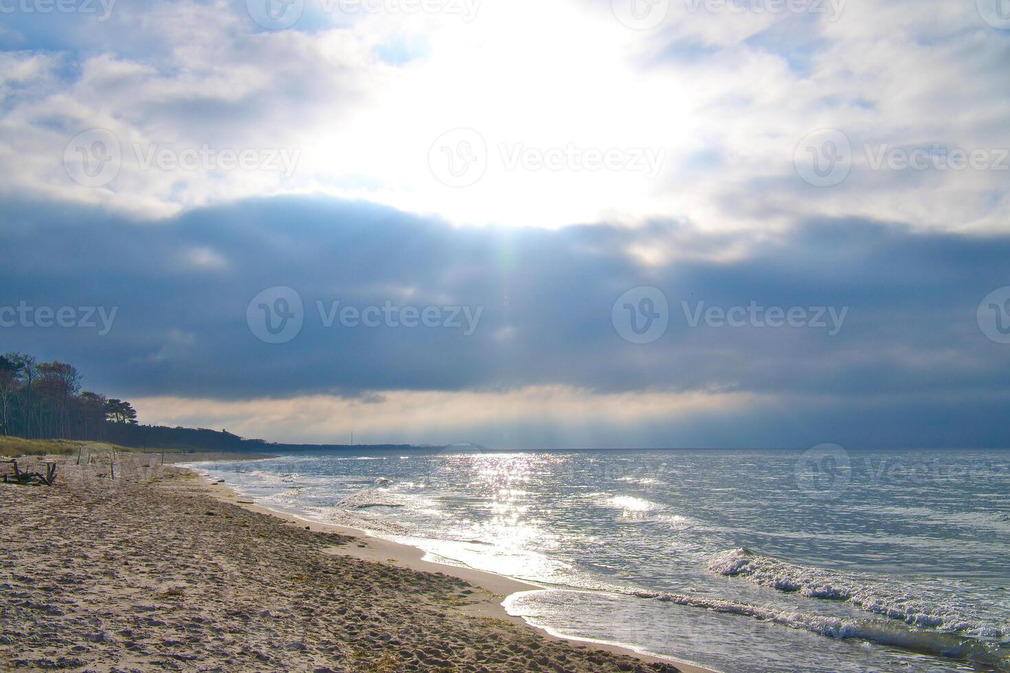 solnedgång på de väst strand på de baltic hav. vågor, strand, molnig himmel och solsken foto