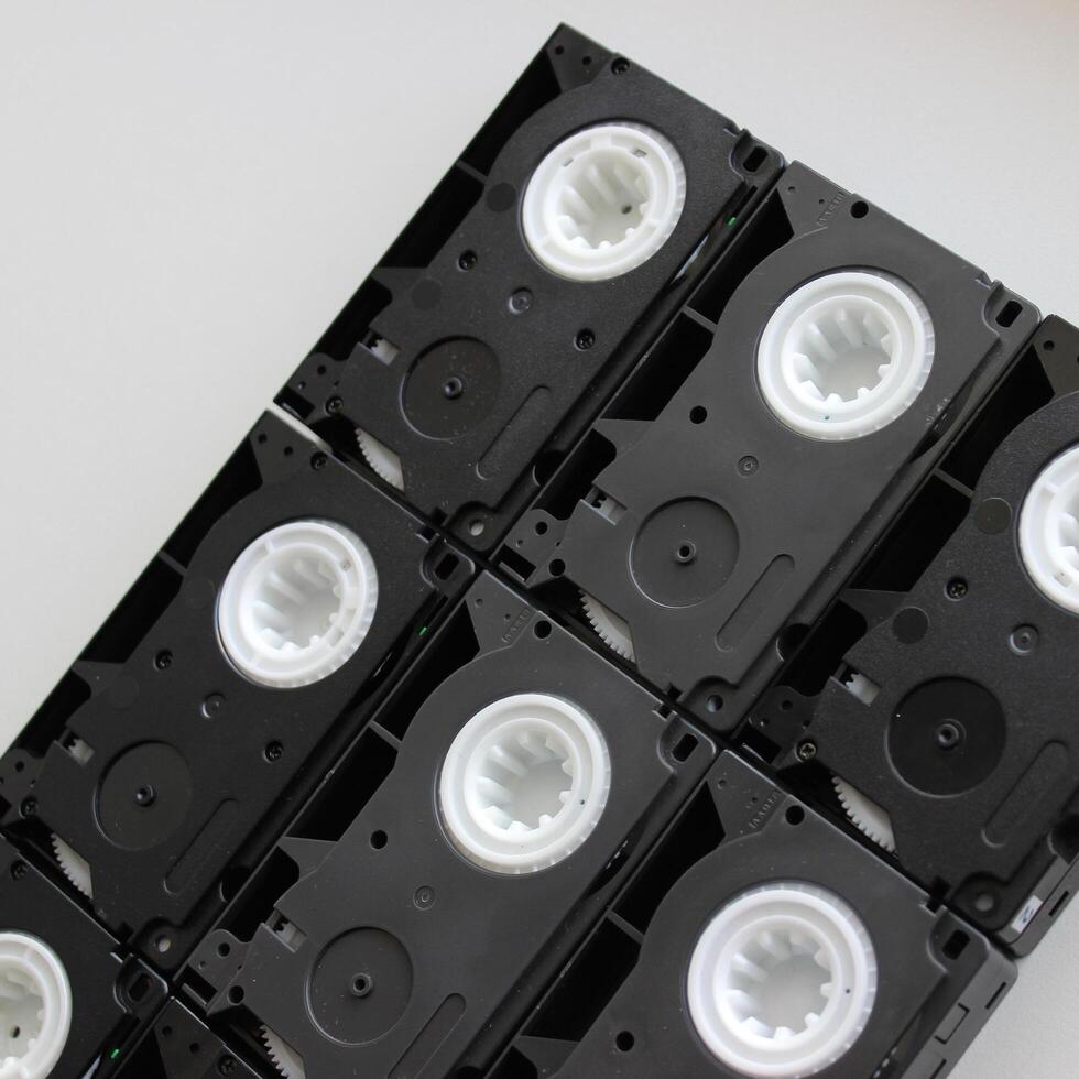 svart blockera tillverkad förbi rader av gammal små tejp video kassetter på vit yta foto