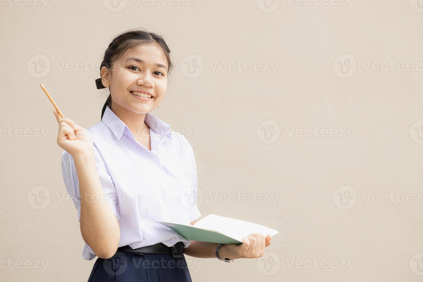 Lycklig smart asiatisk tonåring flicka i skola enhetlig trasa presentatör som visar kreativ aning isolerat bakgrund foto