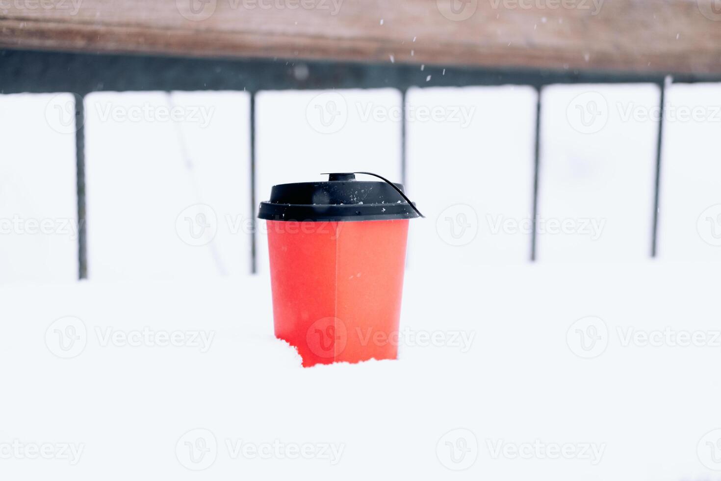 varm kaffe i en röd papper kopp på de snö utanför under en snöfall, närbild foto