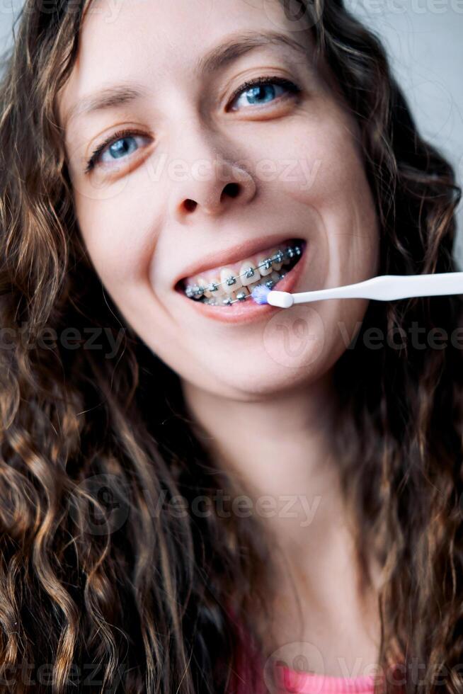 ung kvinna borstar henne tänder med tandställning med en mono-stråle borsta, närbild foto