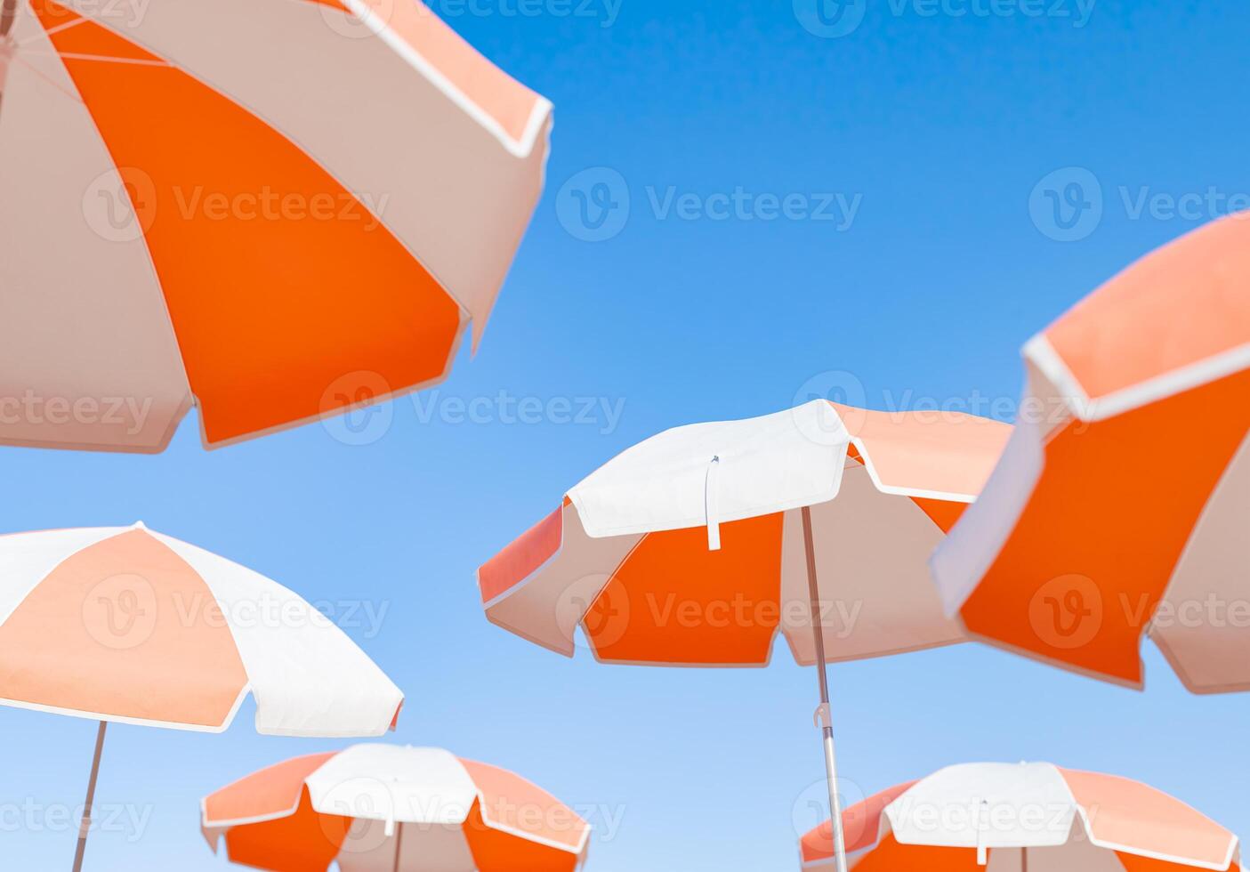 klunga av orange och vit strand paraplyer mot klar himmel foto