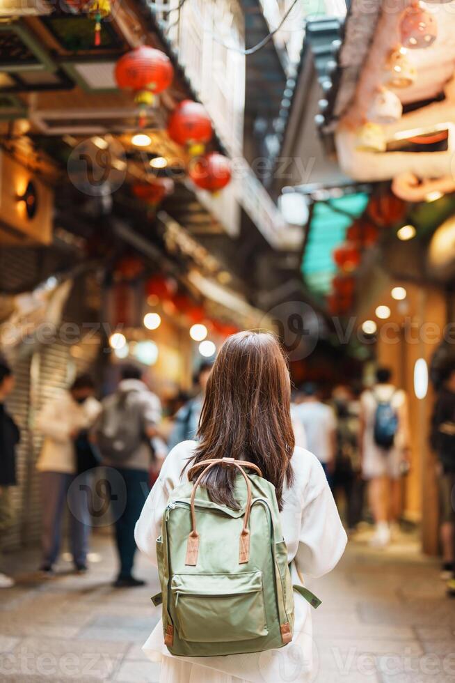 kvinna resande besöker i taiwan, turist med hatt och ryggsäck sightseeing och handla i jiufen gammal gata marknadsföra. landmärke och populär attraktioner nära taipei stad. resa och semester begrepp foto