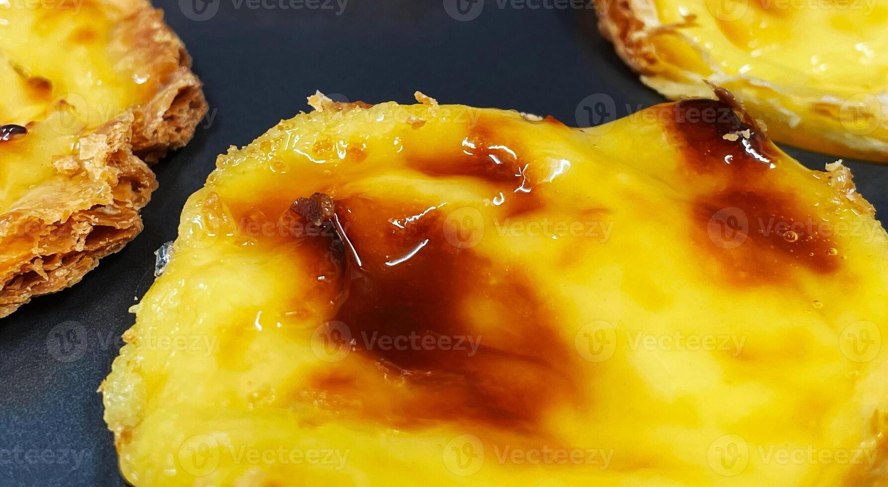 massor av nyligen bakad pastell de nata eller portugisiska ägg syrlig desserter i en bakning maträtt. pastell de belme är en små paj med en Krispig puff bakverk skorpa och en tjock vaniljsås fyllning. små cupcake. foto