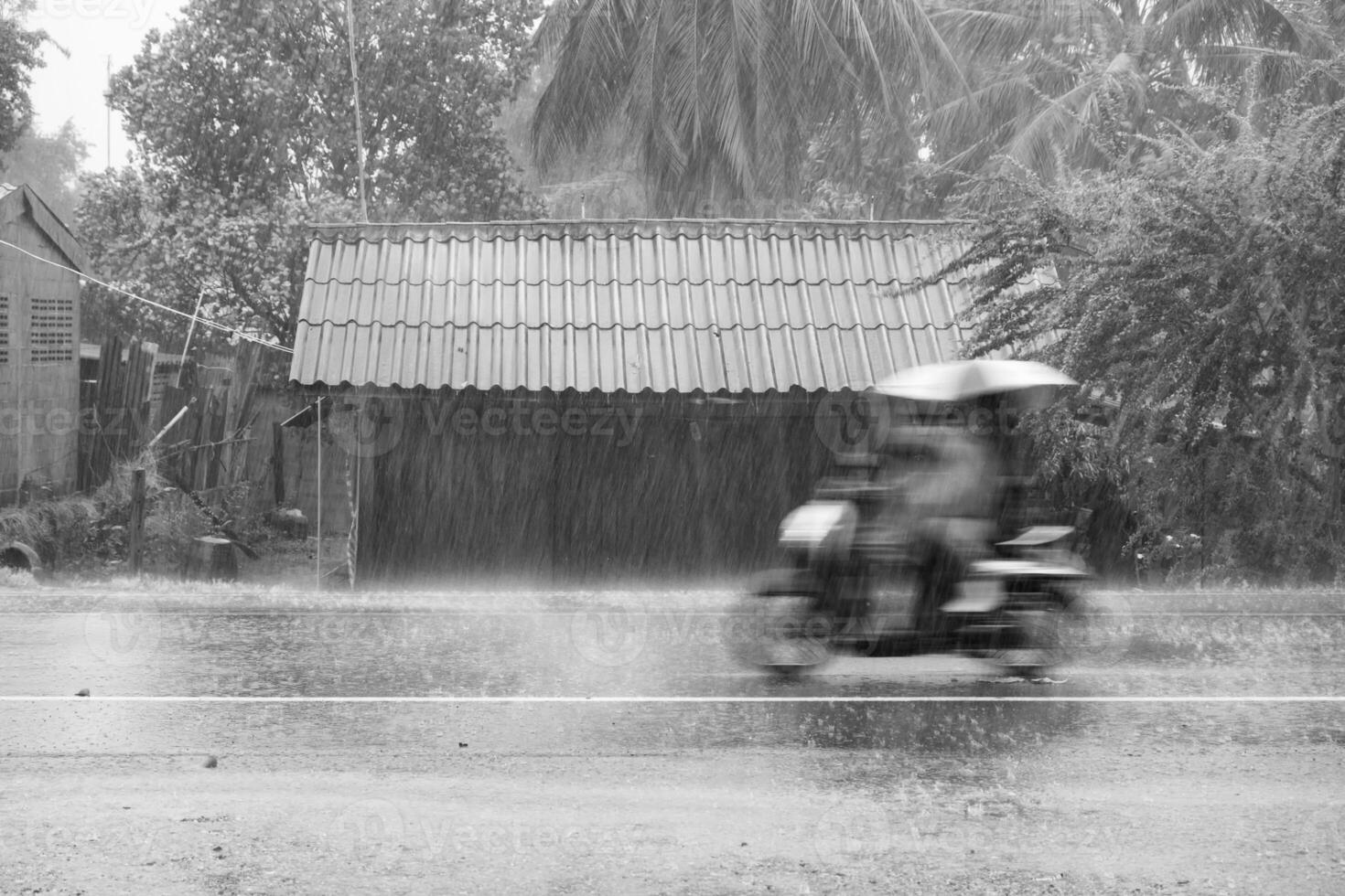 motorcykel rörelse ridning genom storm regn på främre trä- hus i väg gemenskap foto