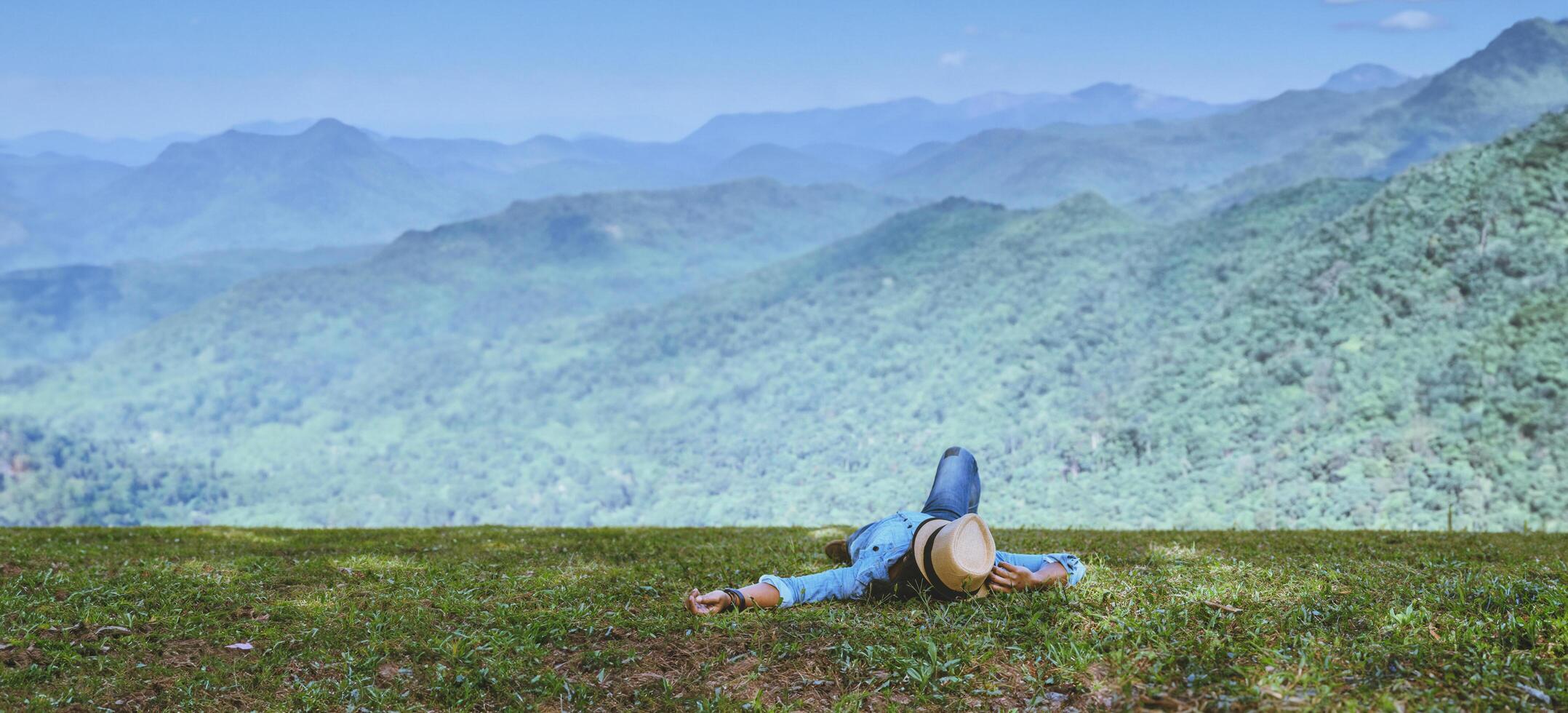asiatisk man resa koppla av i semestern. sova slappna av på gräsmattan på berget. i Thailand foto