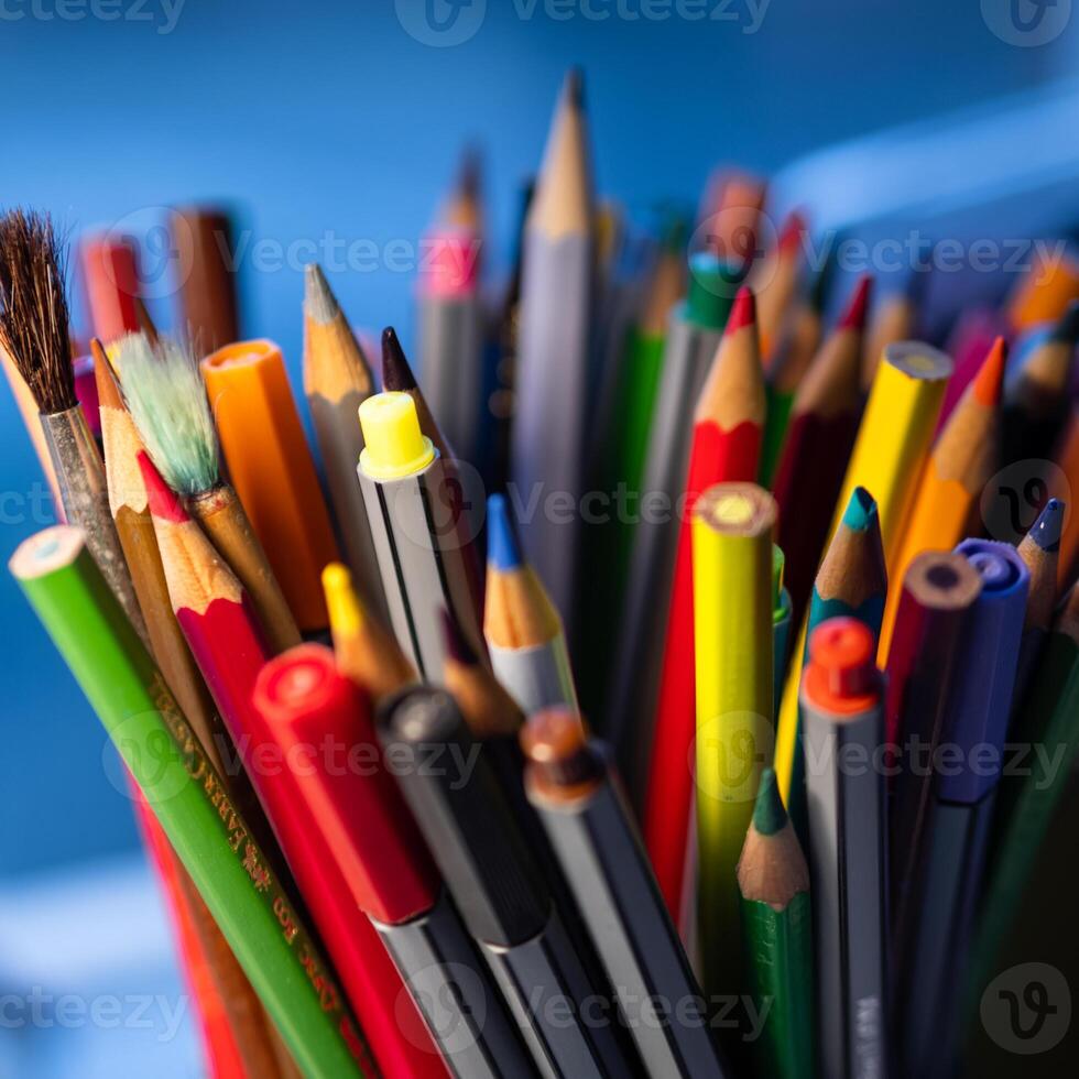 Färg pennor och pennor i en grön behållare foto