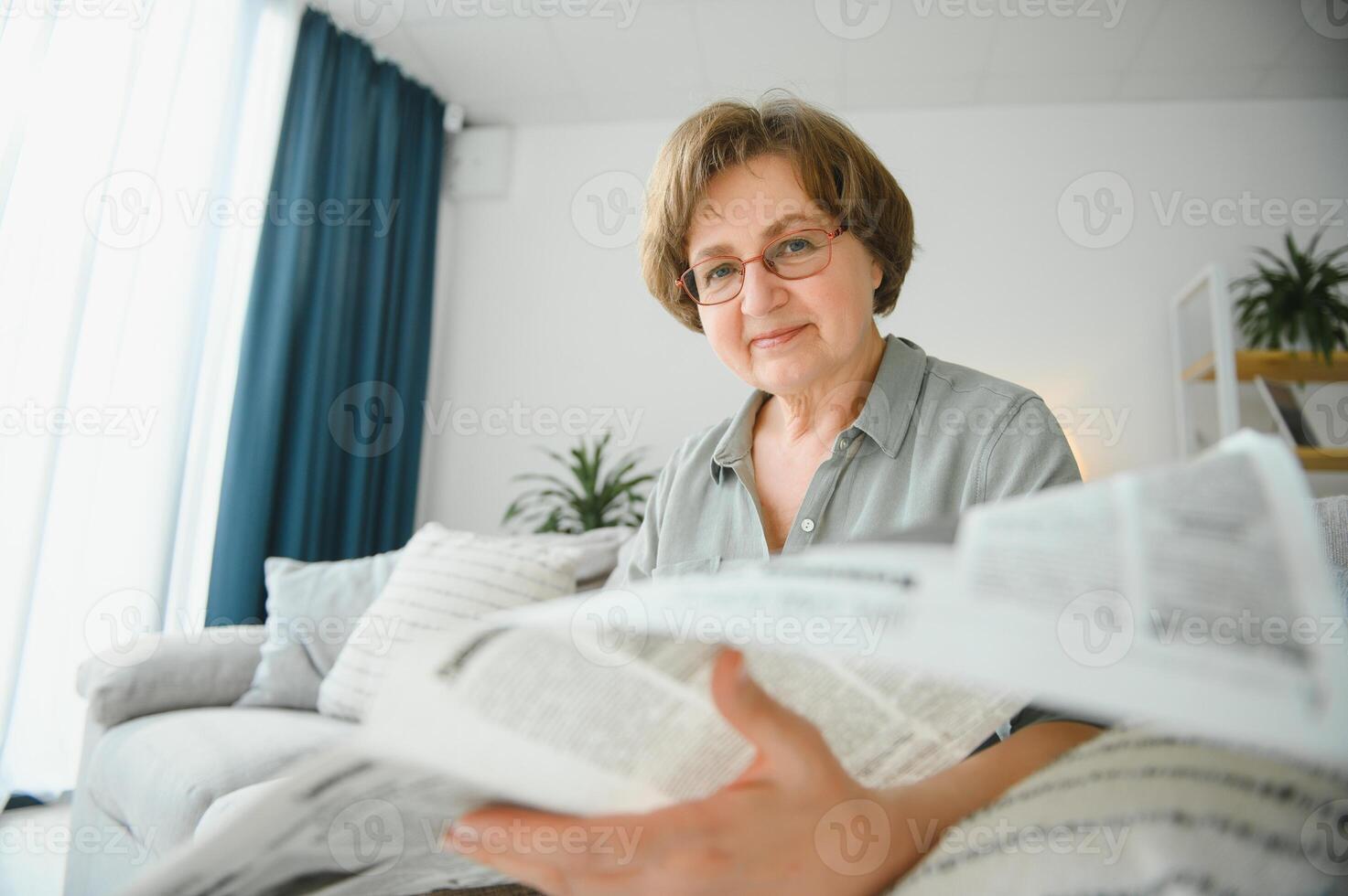 äldre kvinna avslappnande och läsning tidning foto