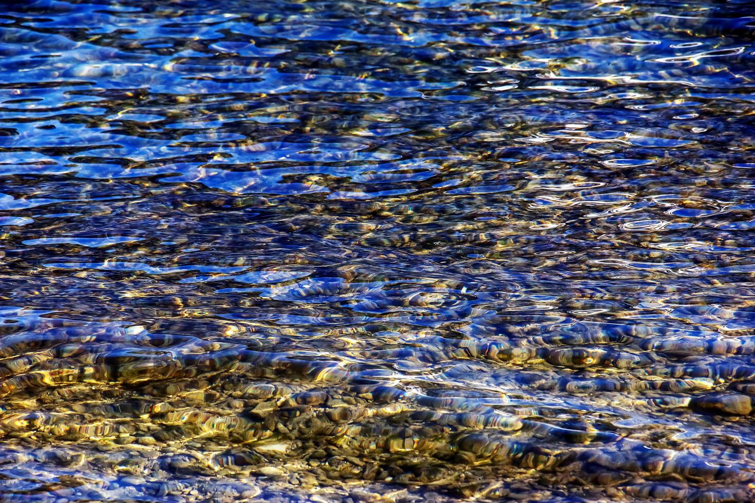 bakgrund av de vatten av sjö Traunsee i de kust område. färgrik textur av stenar under vatten foto