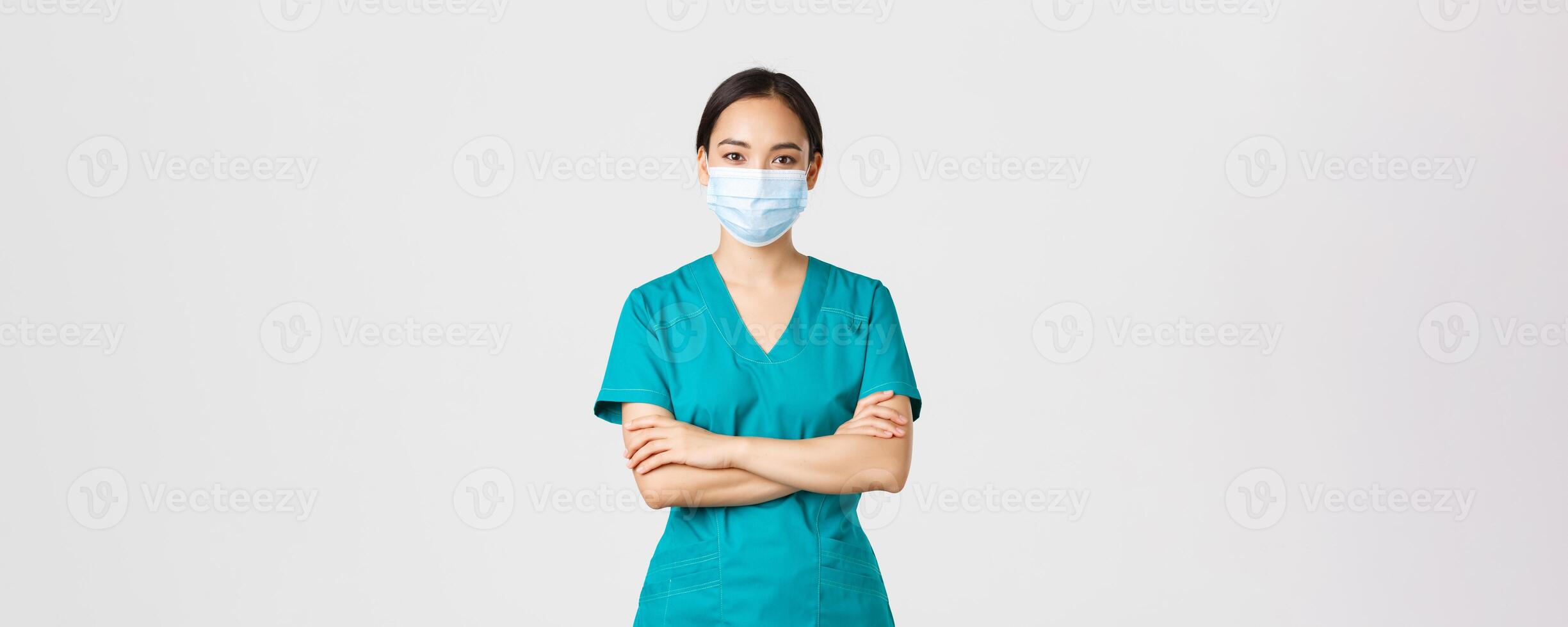 covid19, coronavirus sjukdom, sjukvård arbetare begrepp. leende självsäker asiatisk kvinna läkare, läkare framställning kolla upp, bär scrubs och medicinsk mask, ser fast besluten, vit bakgrund foto