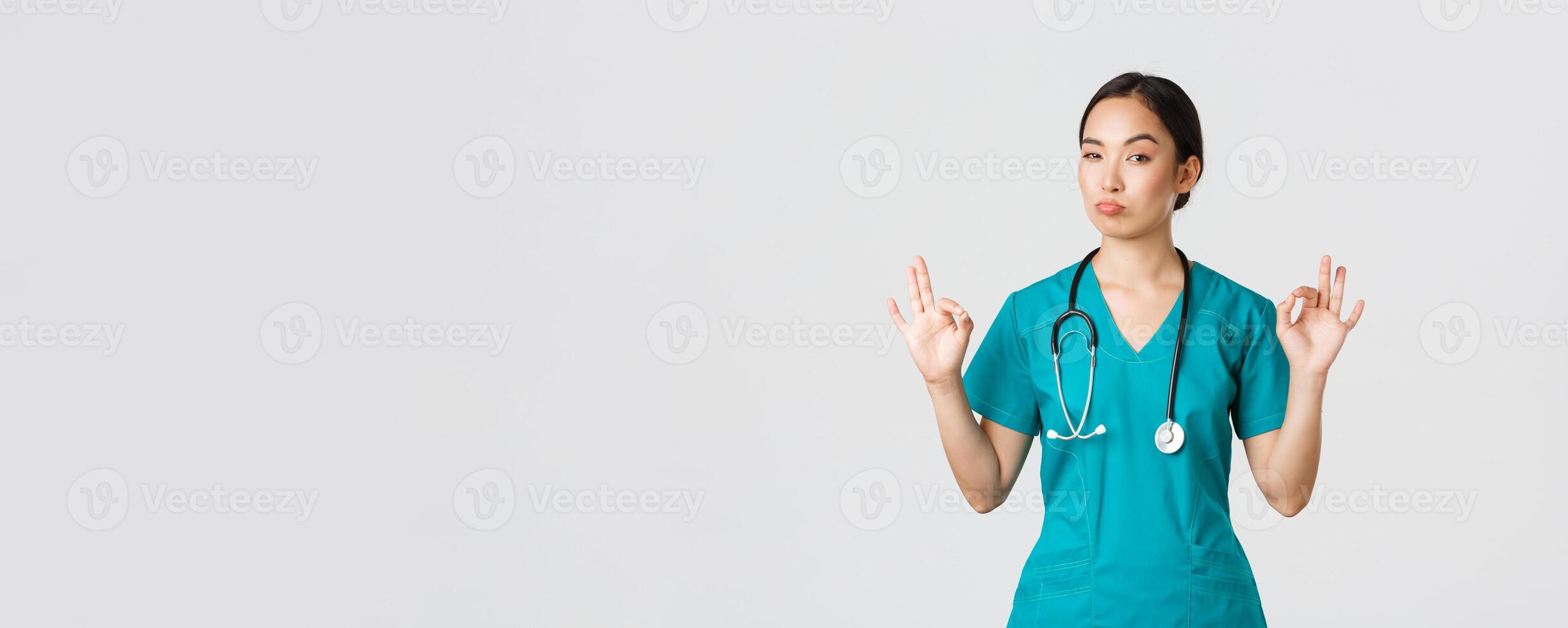 covid19, sjukvård arbetare, pandemi begrepp. imponerad snygg asiatisk kvinna sjuksköterska i skrubbar, läkare visa Okej gest och nicka i godkännande, beröm excellent val, komplimang någon foto
