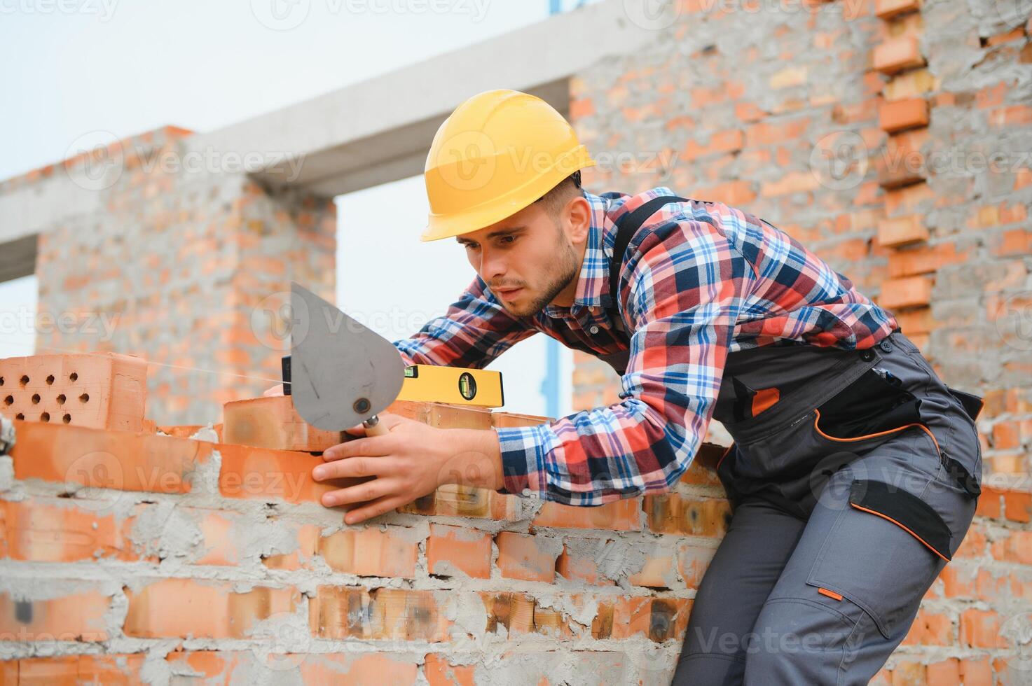 montera tegel vägg. konstruktion arbetstagare i enhetlig och säkerhet Utrustning ha jobb på byggnad foto