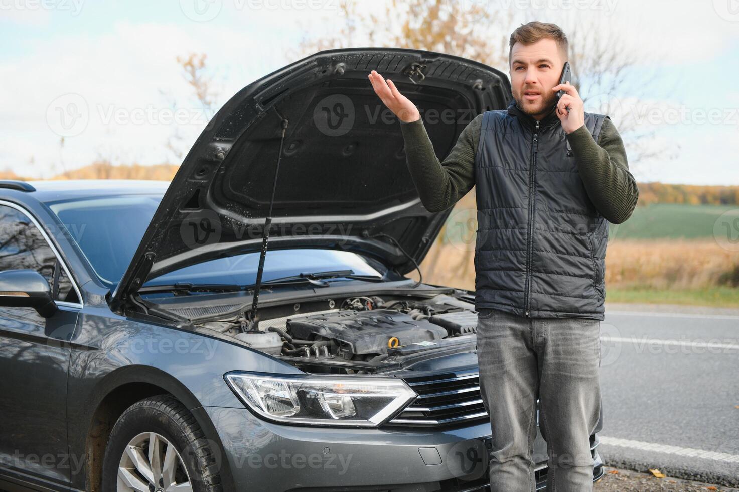 man reparation en bruten bil förbi de väg. man har problem med hans bruten bil på de motorväg vid vägkanten. man ser under de bil huva. bil bryter ner på de autobahn. vid vägkanten bistånd begrepp. foto