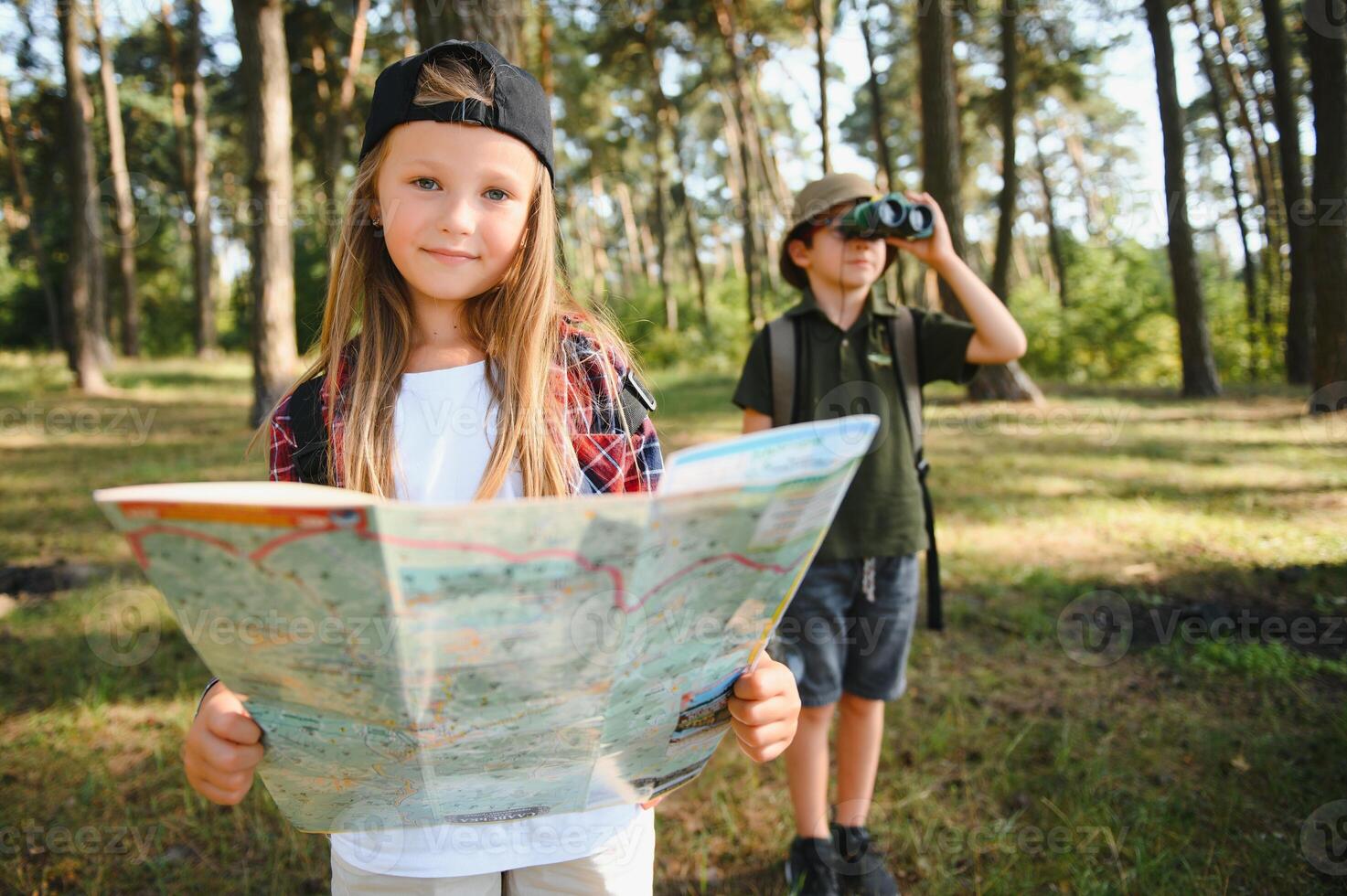 två Lycklig barn har roligt under skog vandra på skön dag i tall skog. söt pojke spana med kikare under vandring i sommar skog. begrepp av äventyr, scouting och vandring turism foto
