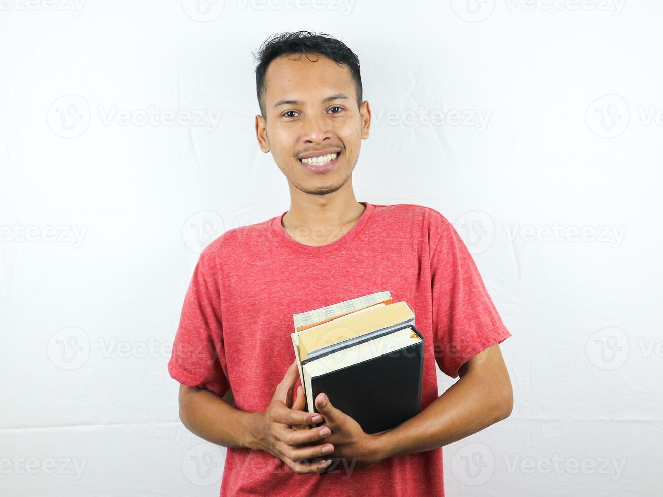 porträtt av ett asiatisk man leende och innehav stack av böcker, isolerat på vit bakgrund. foto