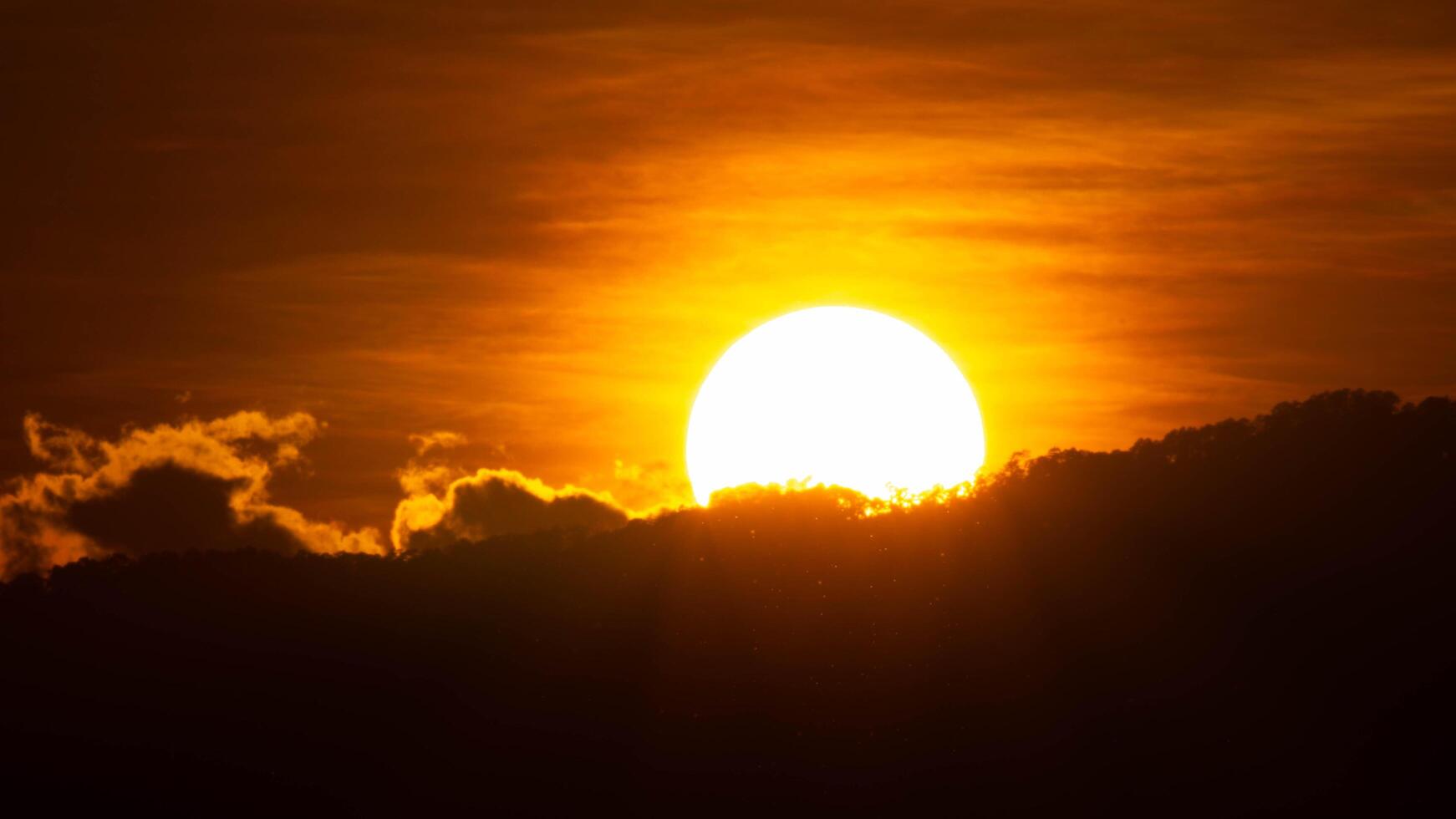 närbild av ljus stor Sol på de himmel med orange lutning färger i en lugnt kväll. foto